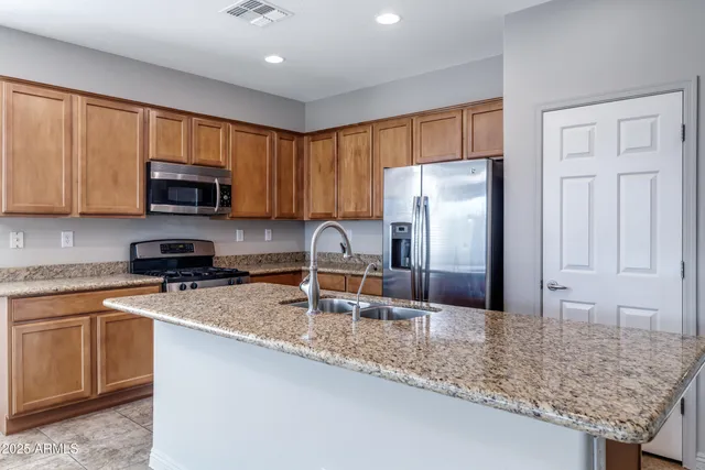 a kitchen with stainless steel appliances granite countertop a stove a sink a microwave a refrigerator and cabinets