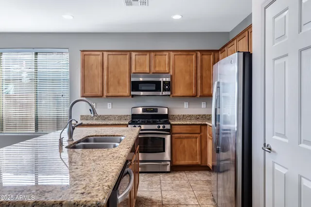 a kitchen with granite countertop a stove sink and refrigerator