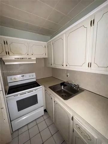 a kitchen with white cabinets and appliances