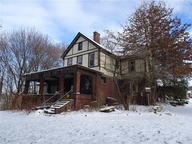 a front view of house with yard and trees in the background