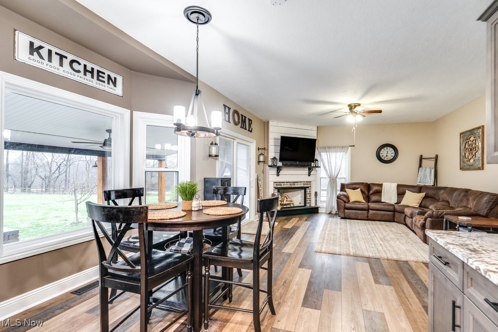 4121 New Milford Road Rootstown, OH 44272 - Photo 20 of 50 Dining space featuring light wood-style floors, ceiling fan with notable chandelier, a fireplace, and baseboards