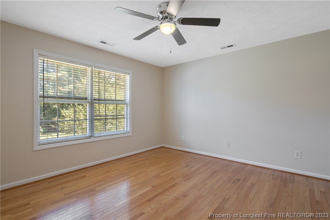 624 Porter Road Hope Mills, NC 28348 - Photo 22 of 45 an empty room with wooden floor ceiling fan and windows