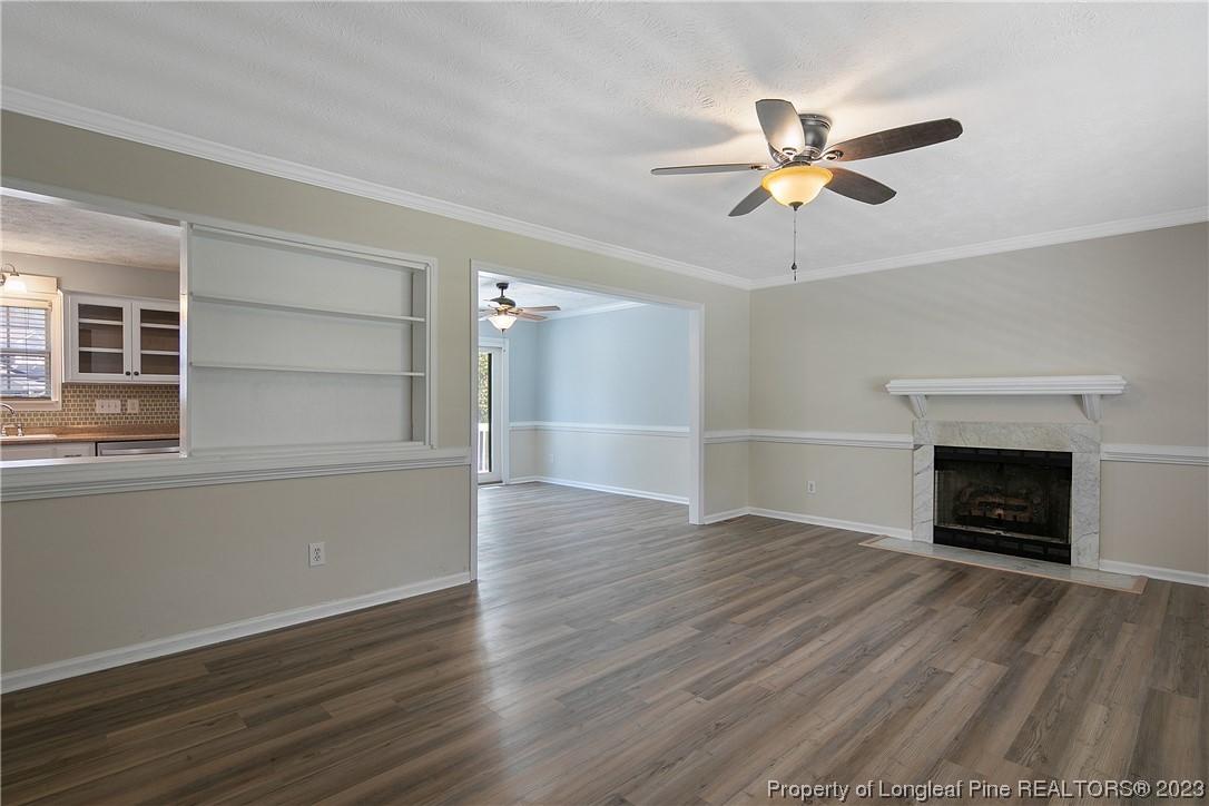 624 Porter Road Hope Mills, NC 28348 - Photo 6 of 45 an empty room with wooden floor a ceiling fan a fireplace and windows