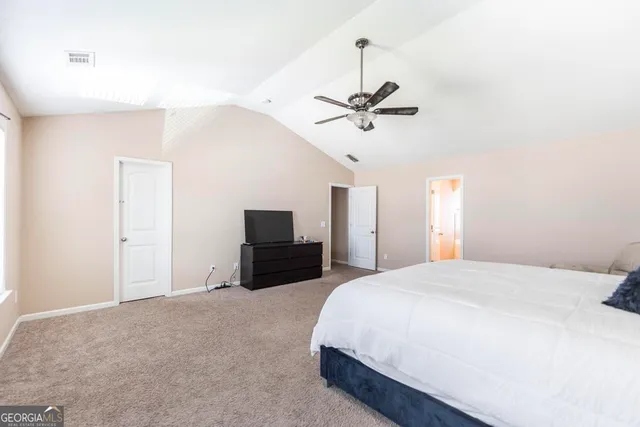 a spacious bedroom with a bed and a flat screen tv