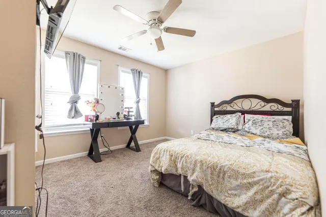 a bedroom with a bed a flat screen tv and a ceiling fan