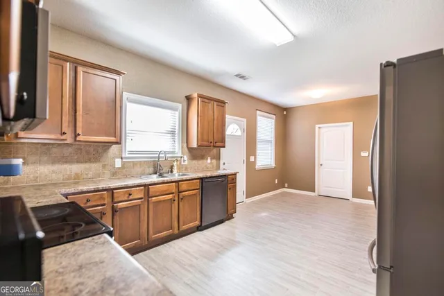 a large kitchen with granite countertop a sink stainless steel appliances and cabinets