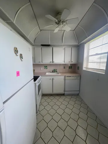 a kitchen with a cabinets a sink and white appliances