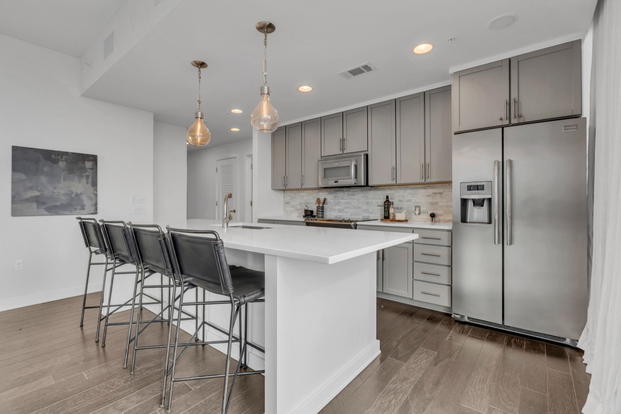 1212 Laurel Street, Unit 1815 Nashville, TN 37203 - Photo 7 of 42 a kitchen with kitchen island granite countertop wooden floors and white cabinets