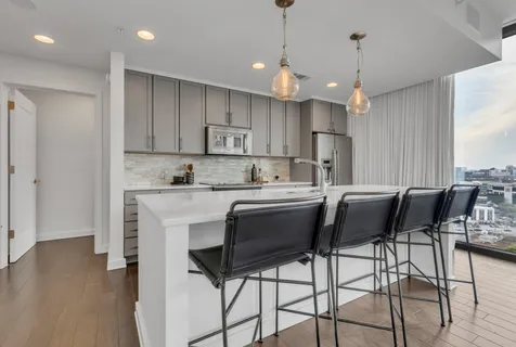 a kitchen with kitchen island a dining table chairs and white cabinets