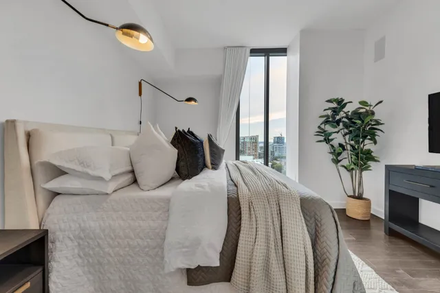 a bed sitting in a bedroom next to a window and a chair