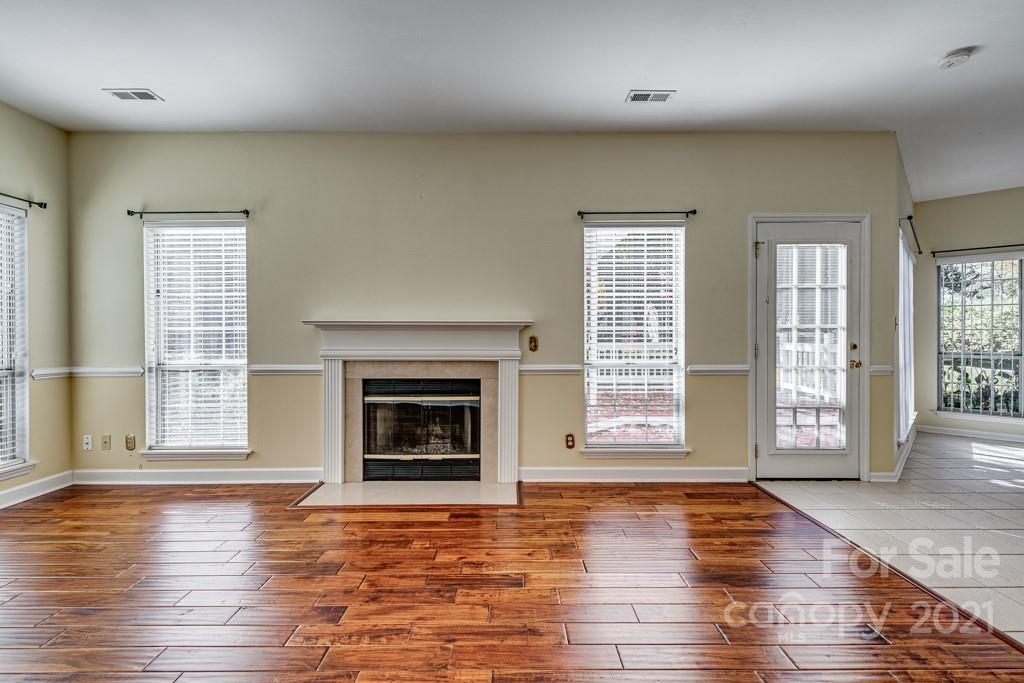 4511 Brownes Ferry Road Charlotte, NC 28269 - Photo 12 of 26 an empty room with wooden floor fireplace and windows