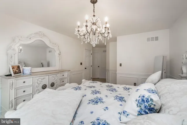 a bedroom with a bed chandelier and a window