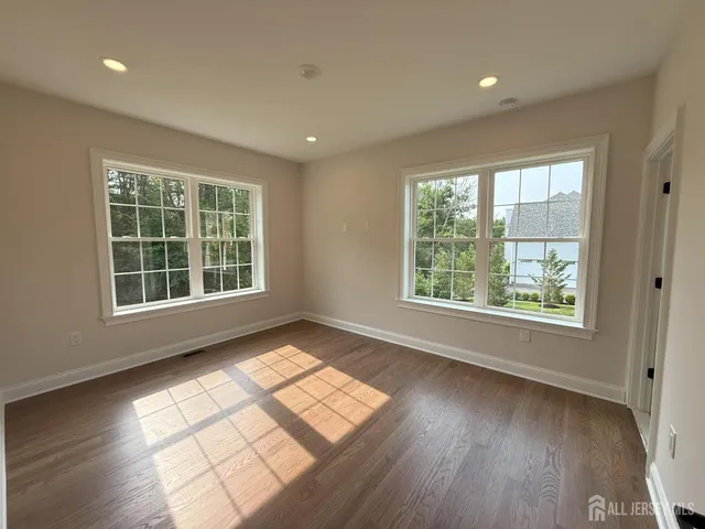 a view of a big room with wooden floor and windows