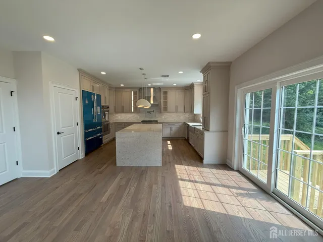 a large kitchen with stainless steel appliances kitchen island a large counter top a sink a stove and a refrigerator