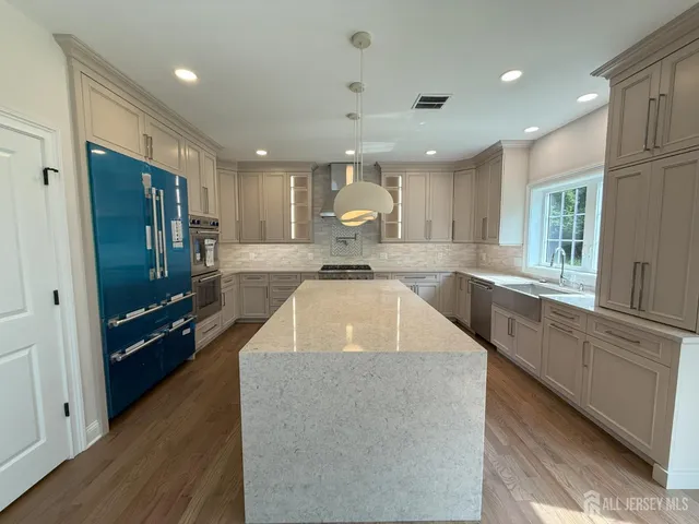 a large kitchen with kitchen island a large counter top space a sink a stove and a refrigerator
