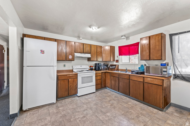 2402 710 North Provo, UT 84601 - Photo 3 of 15 Kitchen featuring L-shaped wood-finish cabinetry and countertops, white appliances, and resilient flooring