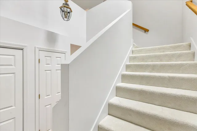 a view of staircase with white walls and a chandelier