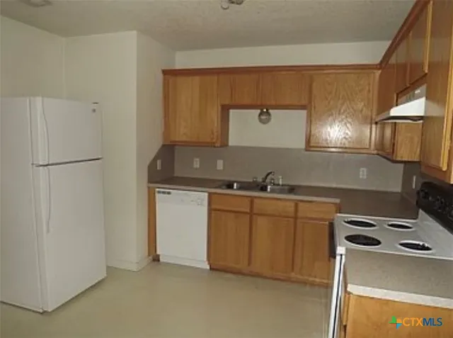 a kitchen with granite countertop a sink and a refrigerator