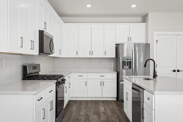 a kitchen with stainless steel appliances granite countertop a sink a stove a refrigerator and cabinets