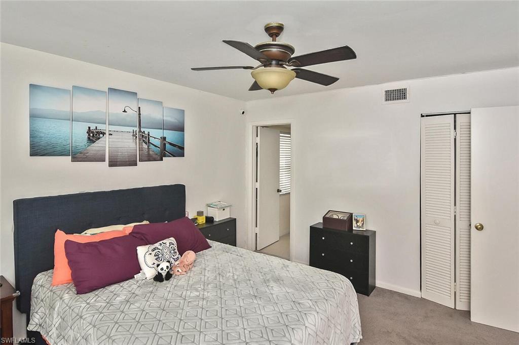 1895 Courtyard Way, Unit B103 Naples, FL 34112 - Photo 13 of 32 a bedroom with a bed and a chandelier