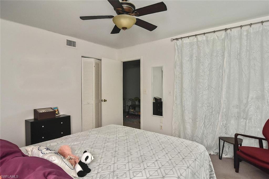 1895 Courtyard Way, Unit B103 Naples, FL 34112 - Photo 14 of 32 a bedroom with a bed and a chandelier