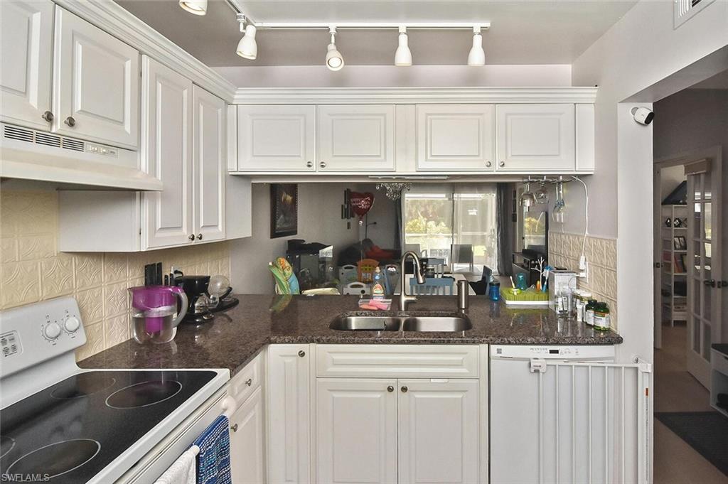 1895 Courtyard Way, Unit B103 Naples, FL 34112 - Photo 22 of 32 a kitchen with white cabinets and sink