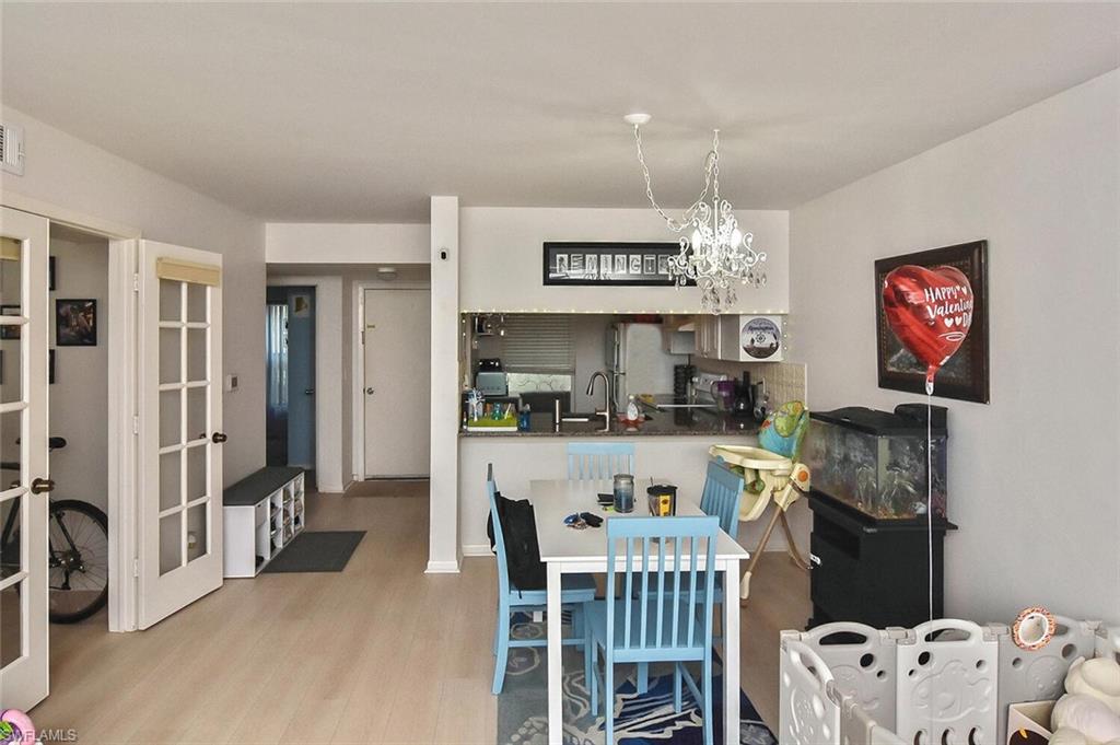 1895 Courtyard Way, Unit B103 Naples, FL 34112 - Photo 25 of 32 a kitchen with stainless steel appliances granite countertop a stove a refrigerator a sink a table and chairs