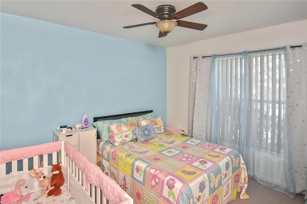 1895 Courtyard Way, Unit B103 Naples, FL 34112 - Photo 27 of 32 a bedroom with a bed and a chandelier