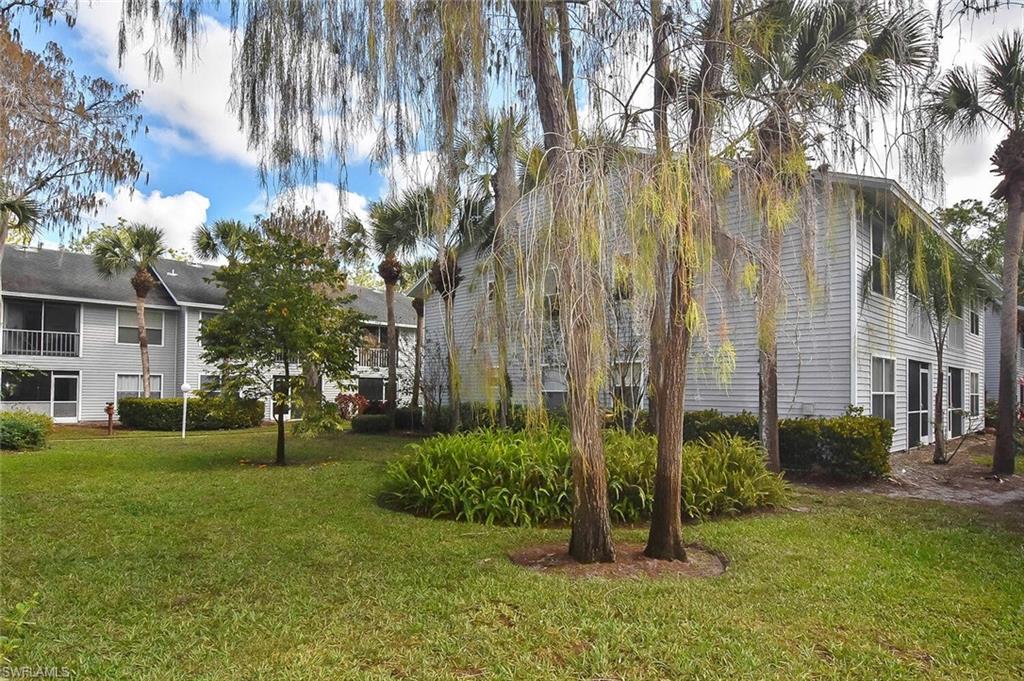 1895 Courtyard Way, Unit B103 Naples, FL 34112 - Photo 4 of 32 a view of a backyard with plants and a large tree