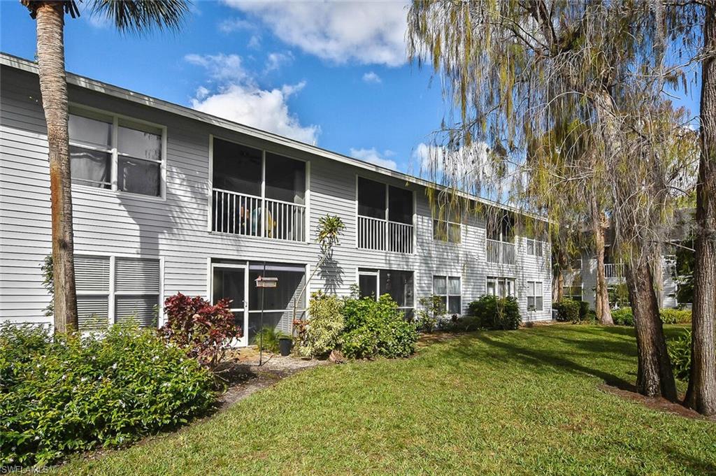 1895 Courtyard Way, Unit B103 Naples, FL 34112 - Photo 5 of 32 a front view of a house with a yard