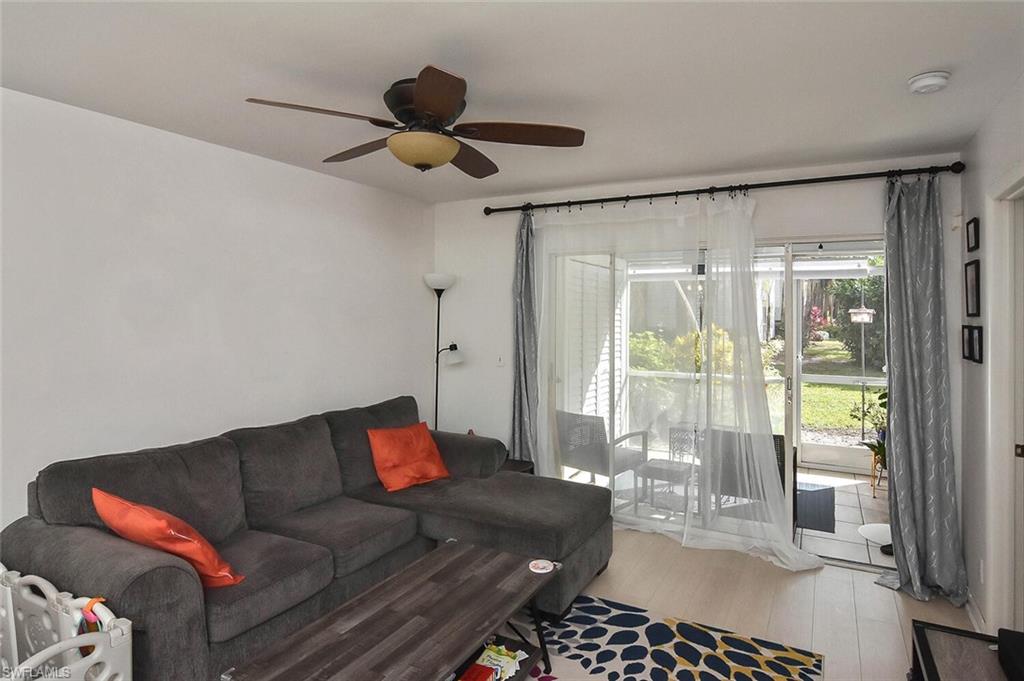 1895 Courtyard Way, Unit B103 Naples, FL 34112 - Photo 7 of 32 a living room with furniture and a floor to ceiling window