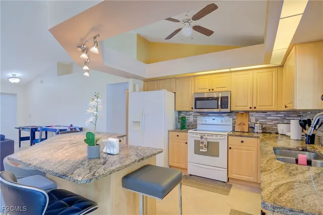 a kitchen with stainless steel appliances kitchen island granite countertop a table chairs and a refrigerator