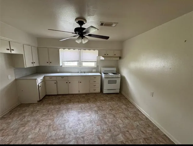 a kitchen with stainless steel appliances a sink a stove a refrigerator cabinets and a window