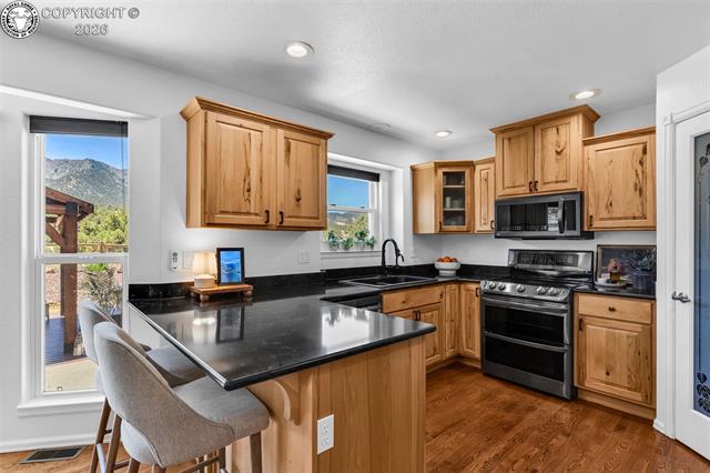 182 Raptor Court Canon City, CO 81212 - Photo 8 of 50 The kitchen is both functional and beautifully upgraded, featuring hardwood floors, a pantry with decorative glass door, and a layout designed for everyday use and entertaining.