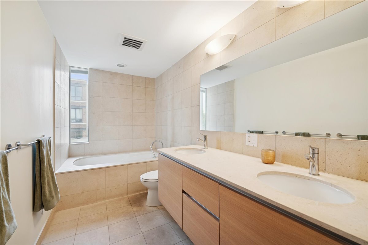 1915 North Damen Avenue, Unit A Chicago, IL 60647 - Photo 20 of 26 a bathroom with a granite countertop sink a toilet and bathtub
