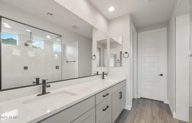 a spacious bathroom with a double vanity sink a mirror and a shower