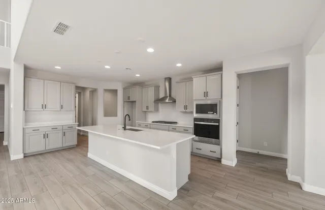 a large white kitchen with kitchen island a sink a stove and refrigerator