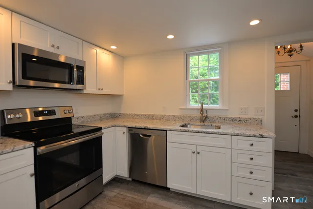 a kitchen with stainless steel appliances granite countertop a stove a sink and a microwave