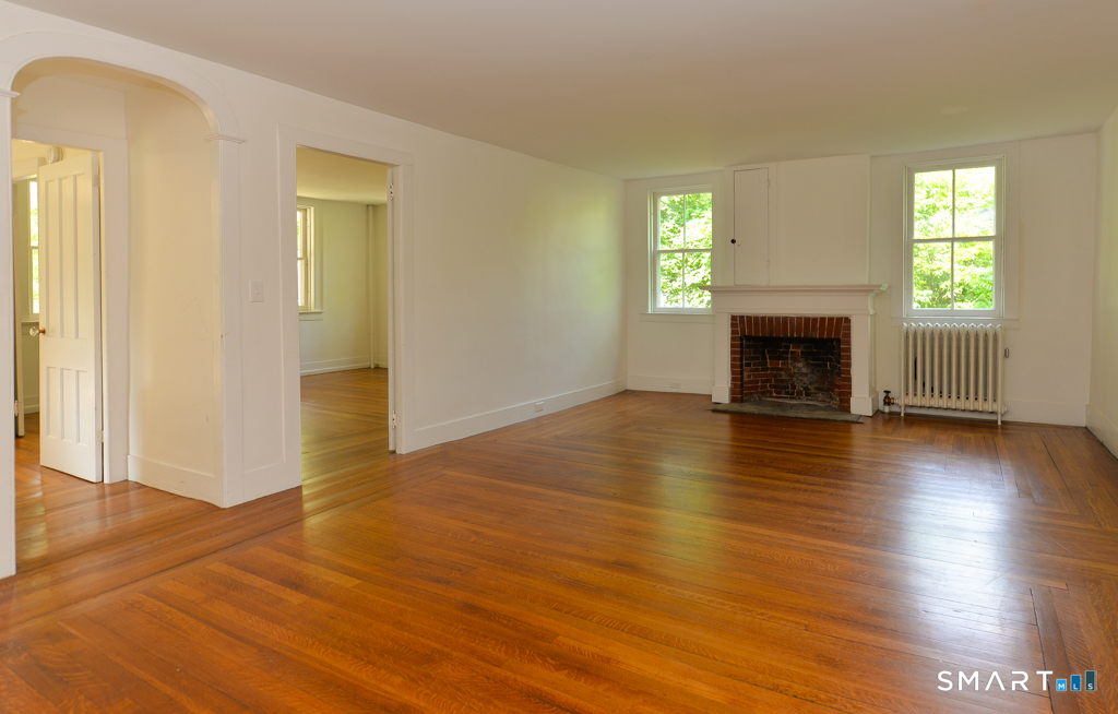 15 Hawkins Road Southbury, CT 06488 - Photo 5 of 26 an empty room with wooden floor fireplace and windows