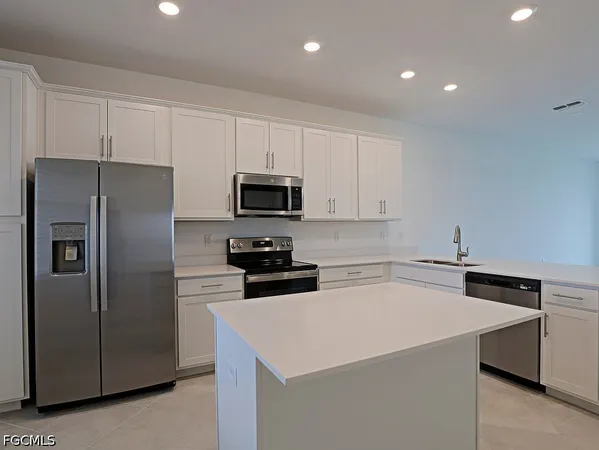 a kitchen with a refrigerator a microwave a sink and cabinets