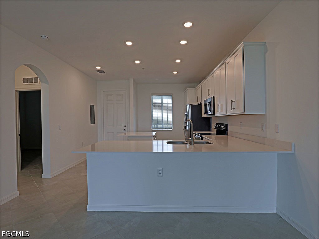43997 Boardwalk Loop, Unit 1843 Punta Gorda, FL 33982 - Photo 3 of 11 a large kitchen with kitchen island a stove a sink a refrigerator and white cabinets