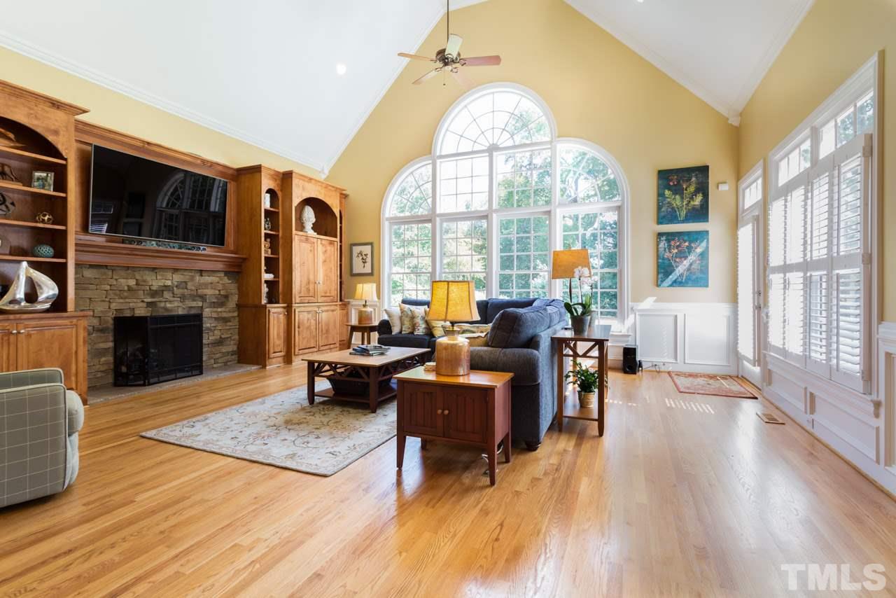 12528 Bayleaf Church Road Raleigh, NC 27614 - Photo 7 of 30 Double Bookcases, Gas Fireplace with Stone Surround, Soaring Vaulted Ceiling, Breath-taking Wall of Windows, Hardwood Floors, and Access to Back Staircase