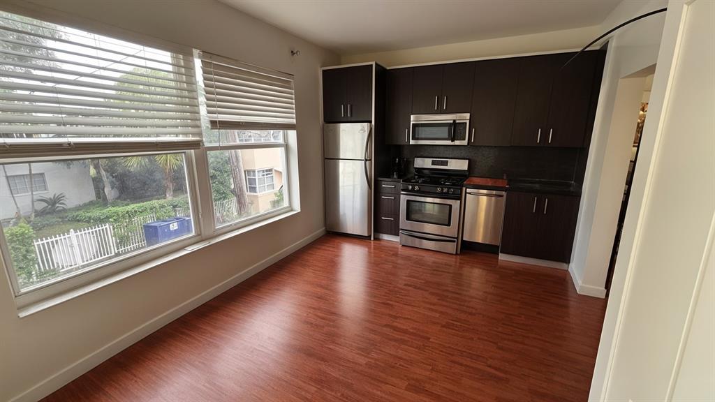 a view of kitchen with stainless steel appliances wooden floor and a window