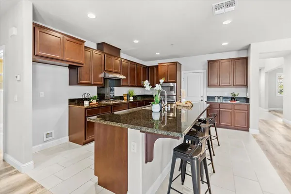 a kitchen with stainless steel appliances granite countertop a refrigerator a stove a sink a dining table and chairs