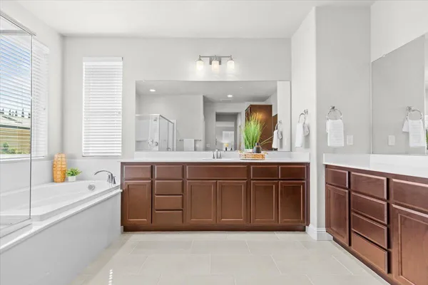 a spacious bathroom with a tub a double vanity sink and a large mirror