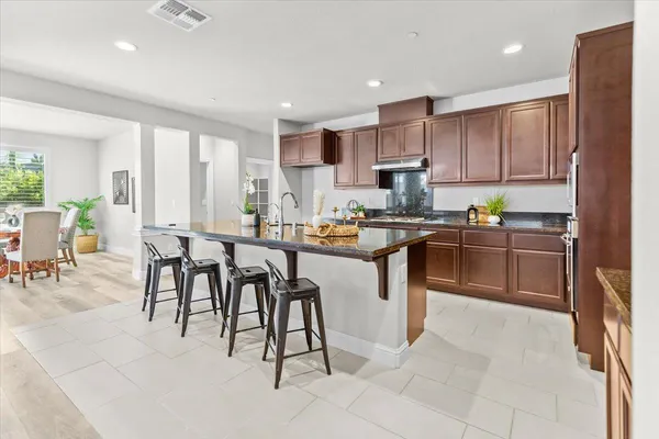 a kitchen with stainless steel appliances granite countertop a table chairs sink and cabinets