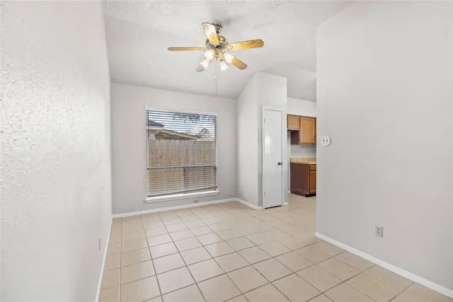 an empty room with chandelier fan and windows