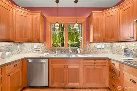 a kitchen with stainless steel appliances granite countertop wooden cabinets a sink and a dishwasher with wooden floor
