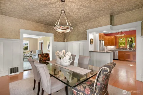 a view of a dining room and livingroom with furniture wooden floor a chandelier