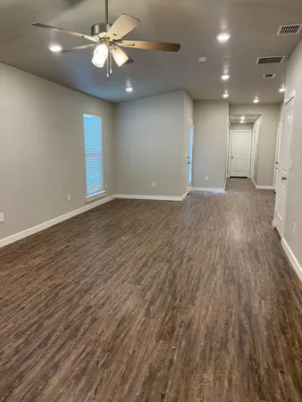 an empty room with wooden floor fan and window